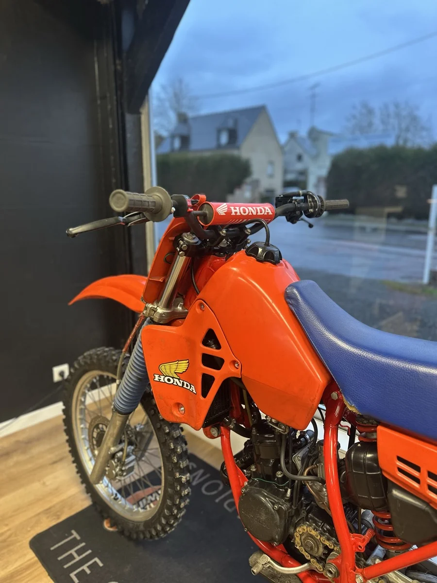 Une Honda tout-terrain orange exposée dans la vitrine de l'atelier